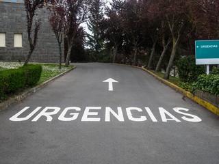 Vehicle access to the emergency department of a hospital. The text on the sign and painted on the ground says "EMERGENCIES" in Spanish.
