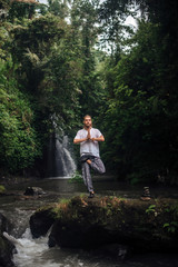 Fototapeta premium Yoga practice and meditation in nature. Man practicing near river