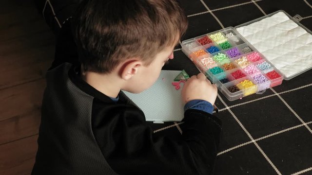 child plays with perler beads. fine motor development
