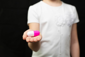 Girl holds a toy pill.