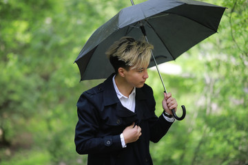 Spring rainy weather and a young man with an umbrella