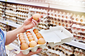 In hands of woman packing eggs in supermarket