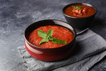 Two bowls with different types of homemade gazpacho. Traditional tomato cool soup with basil on and spicy gazpacho with pepper. Copy space. Red tomatoes soup ready to eat.