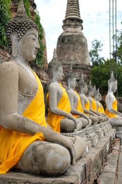 row of old buddha statues in a temple in Ayutthaya Thailand 