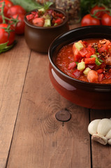 Traditional spanish cold gazpacho tomato soup on wood background with place for text. Ingredients around the cooked soup. Recipe, menu. Vegetarian healthy food.