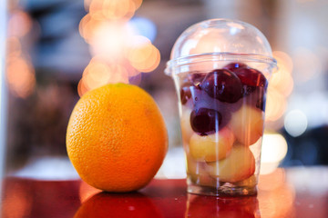 Fruit salad in a clear plastic Cup and an orange