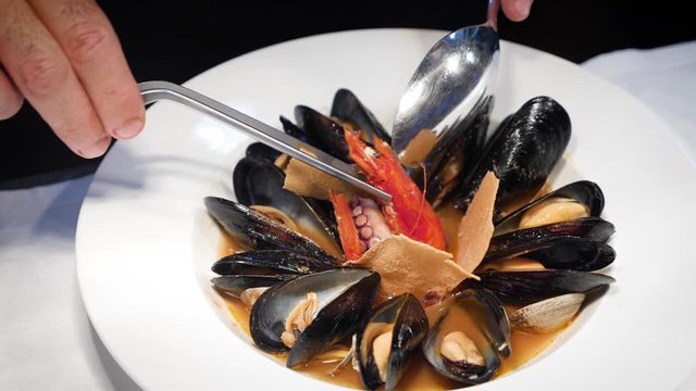 Cuoco prepara zuppa di cozze guarnita con pane carasau della sardegna