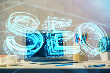 Double exposure of table with computer and seo drawing hologram. Search optimization concept.