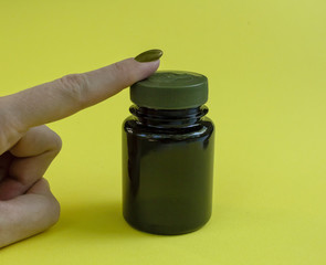 A dark medicine jar lies on a yellow background.