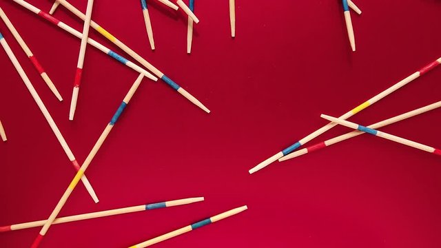 Top View of Mikado pick-up sticks falling on red surface, Slow Motion