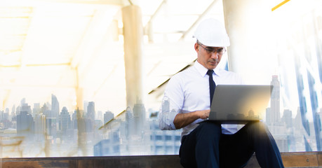 Professional team engineering. Confident architect at construction sit. Portrait Confident architect man working on laptop computer with white safety hardhat at construction site