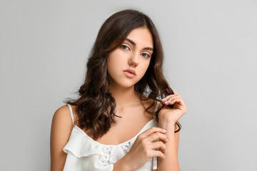 Naklejka premium Young woman with beautiful curly hair on grey background