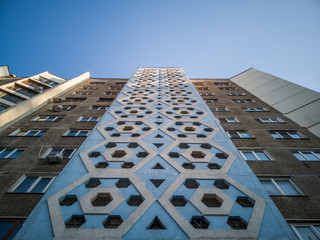 Bottom-up view of symmetric facade of old soviet multistorey typical concrete apartment.