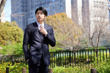 ビルを背景に立つ日本人男性ビジネスマン