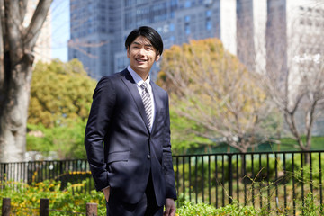 ビルを背景に立つ日本人男性ビジネスマン