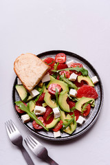 Vegetarian salad with avocado, grapefruit, tomato, feta cheese and arugula. Healthy nutrition. Selective focus