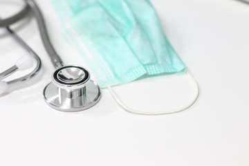 Stethoscope and green mask on white background