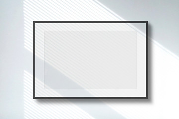 Blank picture frame on white wall with window shadow light as template for event promotion, design presentation, self portfolio etc.