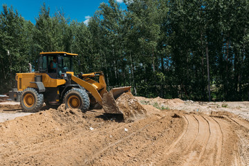 large yellow tractor at a construction site a bulldozer cleans the site with a bucket