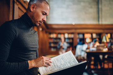 Smart intellectual male professor reading book making researcher for work while standing in public...