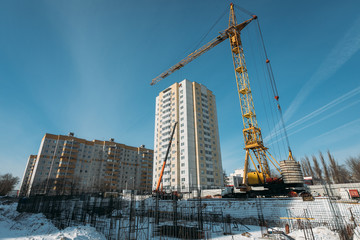 Fototapeta na wymiar yellow construction cranes and the foundation of a multi-storey residential building in winter