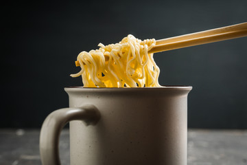 Instant noodles in cup on the rustic background. Selective focus. Shallow depth of field. 