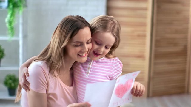 Caring daughter give mom self made greeting card with drawing heart. Shot with RED camera in 4K