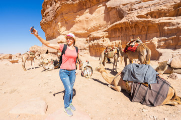Tourist making selfie with camels in desert. Wadi Rum, Jordan.