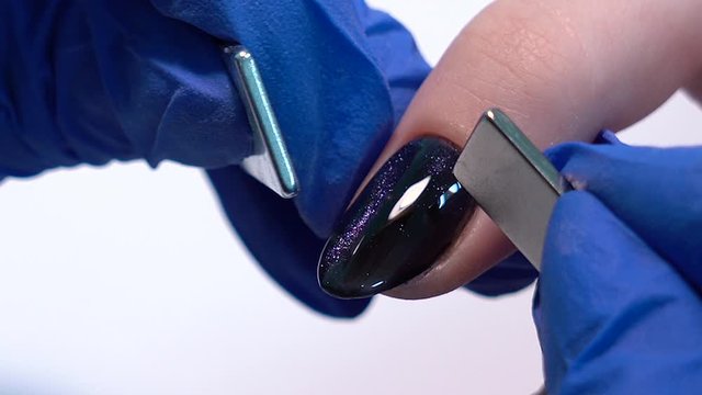 Closeup view 4k video of professional colorful glossy brilliant holiday manicure at fingers of young woman. Modern trendy shiny amazing cat eye effect nail design on black gelpolish.
