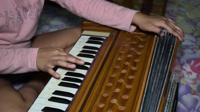 CloseAn Indian child playing musical instrument Harmonium