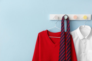 Stylish school uniform hanging on color wall