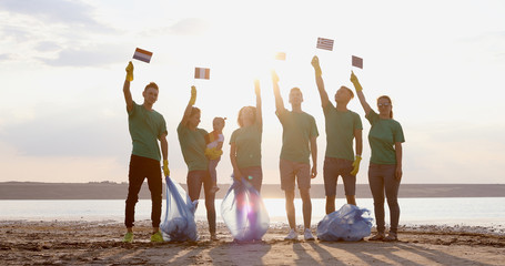 People in green T-shirts stand together and raise the flags of the European Union.