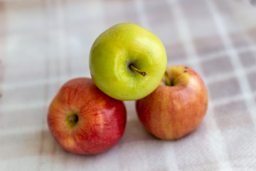 Three apples, one green and two red-yellow on a light background.