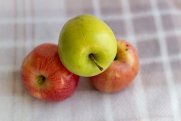 Three apples, one green and two red-yellow on a light background.