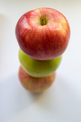 Three apples, one green and two red-yellow on a light background.