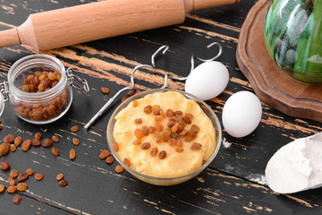 Bowl with sweet dough and products on table