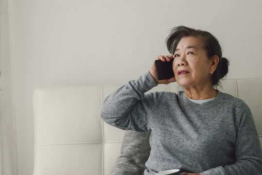 Happy Asian senior woman talking a phone and holding drink cup, stay home stay safe concept.