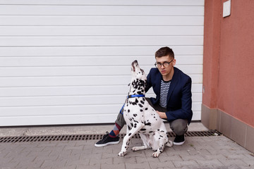 A young man having troubles holding a dalmatian dog on a leash. Naughty, barking dog pulling on...