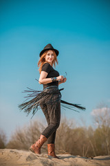 Fashionable outfit of redhead woman in jeans with fringe belt and Fedora hat