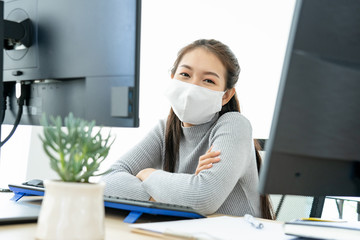 Fototapeta na wymiar Asian business woman wear mask looking camera using laptop two computer video conference meeting talking working with coworker from home during infectious coronavirus or covid-19 spread