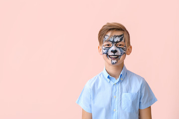 Funny little boy with face painting on color background