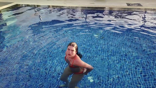 Girl brunette swims in a blue pool