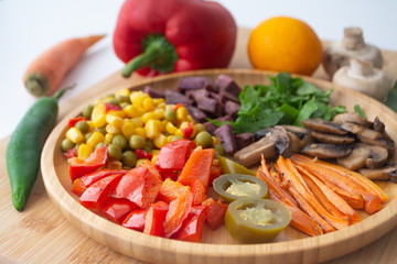 Nutritious and healthy buddha fajita bowl with sweet corn, green peas, red bell pepper, jalapenos, carrots, mushrooms, spinach, beetroot and sweet potatoes surrounded by ingredients and lemon
