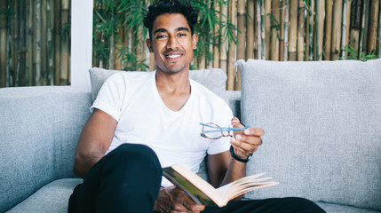 Young man sitting on sofa and smiling at home
