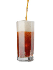Dark beer flows into the glass in a stream with bubbles and copious foam, on a white background
