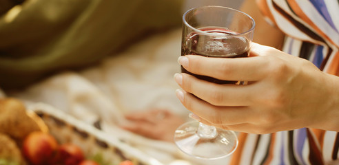 Hand with a glass of red vine on picnic. close up. Banner for website
