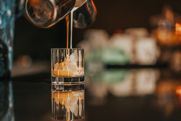 Iced americano preparation, pouring milk and coffee into iced glass
