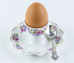 A chicken egg lies on a beautiful porcelain stand. Nearby lies