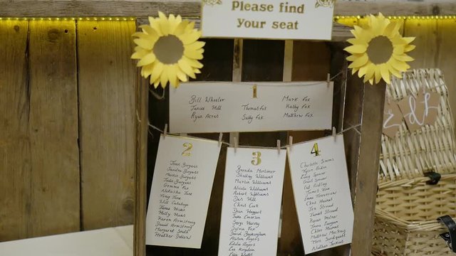 Creative Wedding Seating Chart List Hanging On A Wooden Box With Decorated Paper Sunflowers For Guests Reference - Closeup shot