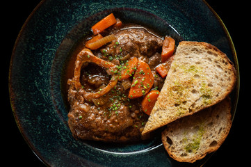 Ossobuco meat with stewed vegetables and bread